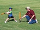 Dad and son playing T-ball in the park.