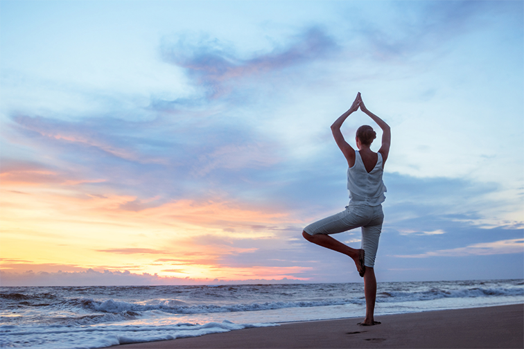 woman doing yoga on beach