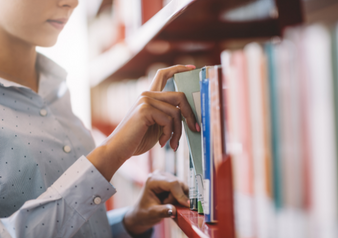 person selecting book from shelf