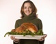 Girl holding a platter with a cooked turkey for the holidays