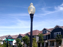 Street light with a row of two story houses behind it and a blue sky