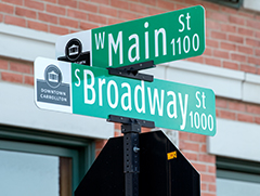 Street signs for West Main Street and South Broadway Street on top of a stop sign with a building behind it