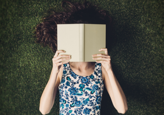 woman reading book in grass